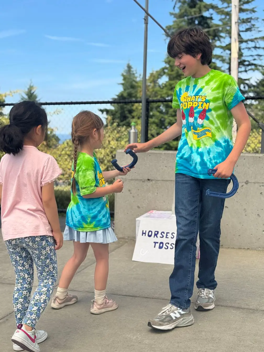 Older student passing horseshoe to younger student